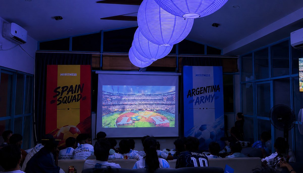 Screening night at Escapeer Community House — paper lanterns and a full room watching the match